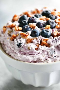 a close up of a bowl of food with blueberries and walnuts on top