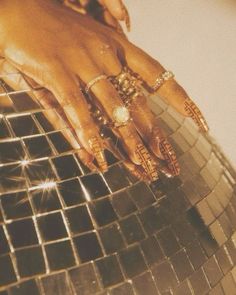 a woman's hands with rings on top of a shiny mirror plated surface