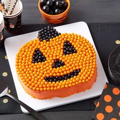 a cake decorated with orange and black candy sits on a table next to halloween decorations