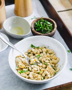 a white bowl filled with pasta next to two small bowls and spoons on a table