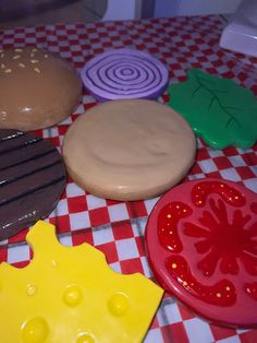 there are some cookies and doughnuts sitting on the checkered tablecloth,