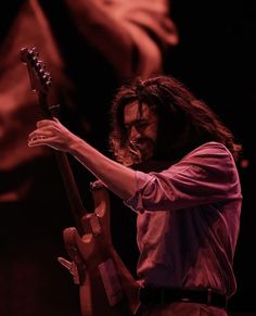 a man with long hair playing an electric guitar