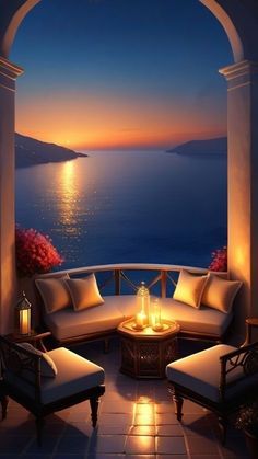 an outdoor seating area overlooking the ocean at night with lit candles and lanterns on it