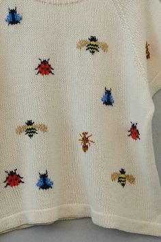 a white sweater with colorful bugs on it