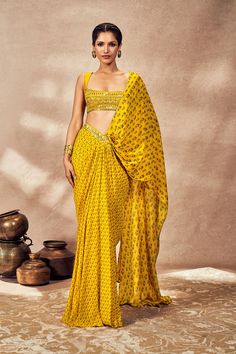 Presenting the yellow pixie dust drape sari, a stunning blend of modernity and traditional charm. This pre-stitched sari showcases an all-over digital print, ensuring effortless elegance with a center back enclosure for easy wear. The sheer printed palla is beautifully embellished with kinari gota, adding a touch of cultural richness. A waistband adorned with sequin and dori embroidery enhances the sari's aesthetic appeal, ensuring a secure and stylish fit. The accompanying blouse features a sco Drape Sari, Dori Embroidery, Saree Georgette, Sari Design, Diwali Outfits, Luxury Wear, Indian Fashion Designers, Effortless Elegance