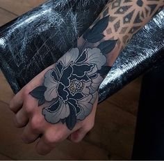 a person with a tattoo on their arm holding a black and white flower in her hand