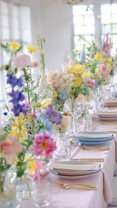 a long table with plates and vases filled with colorful flowers on top of it