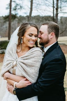 a bride and groom hugging each other in front of trees