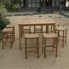 a wooden table and chairs sitting in the sand