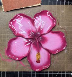 a pink flower sitting on top of a cutting board