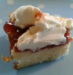 a piece of cake with whipped cream and jelly on it sitting on a blue plate