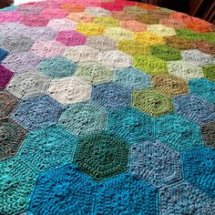 a multicolored crocheted blanket is laying on the floor