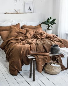 an unmade bed in a white room with brown sheets and blankets on the bed