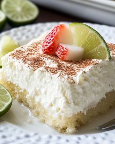 a piece of cake with strawberries and limes on it sitting on a plate