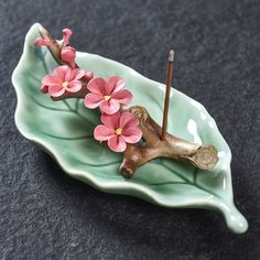 a green plate with pink flowers on it and two sticks sticking out of the top