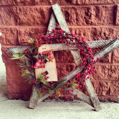 a wooden star decorated with berries and a snowman decoration on the side of a building