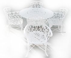 the table and chairs are all white with intricate designs on each side, as well as an umbrella