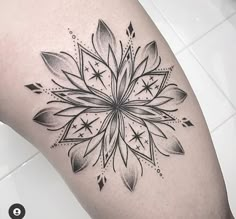 a black and white photo of a flower tattoo on the thigh, with stars in the middle