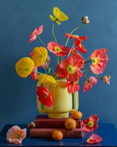 a yellow vase filled with flowers on top of books