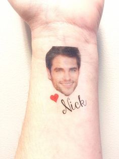 a man's face with a heart on his left wrist and the word sick written in black ink