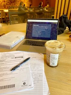 a laptop computer sitting on top of a wooden table next to a cup of coffee