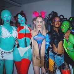 several women in bodysuits and costumes posing for a photo with their faces painted