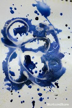 blue and white ink is splattered onto the surface of a plate with black spots