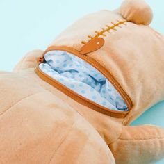 a stuffed animal laying on top of a blue floor next to a zippered pouch