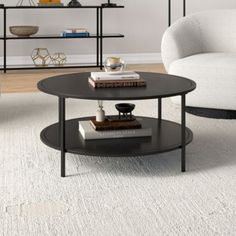 a living room with two white chairs and a black coffee table in front of a bookshelf