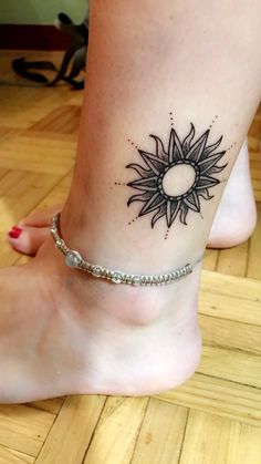 a woman's foot with a small sun tattoo on the side of her leg