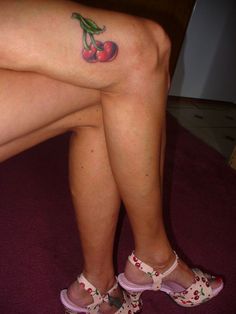 a woman's legs with cherries tattooed on them