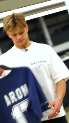 a young man holding up a blue jersey