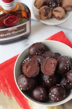 a bowl full of chocolate truffles next to a bottle of brandy