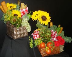 two baskets filled with flowers and vegetables on top of a black cloth covered tablecloth