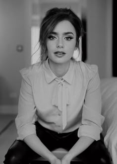 a black and white photo of a woman sitting on a bed with her legs crossed