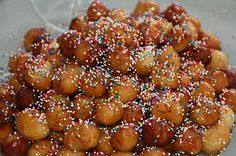 a pile of donuts covered in sprinkles on top of a glass plate