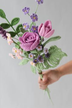 a person holding a crocheted bouquet of flowers