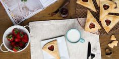 a table topped with pastries next to a bowl of strawberries