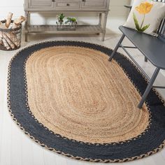 a black and beige rug in the corner of a room with a chair, table and dresser