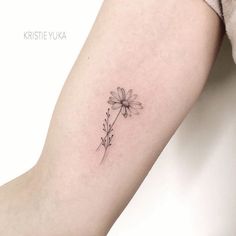 a small daisy tattoo on the left arm