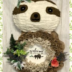 a stuffed slotty bear holding a wreath with the words welcome to you on it