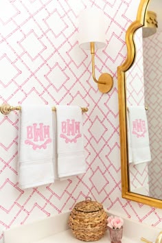 a bathroom with pink and white wallpaper, gold fixtures and towels on the rack