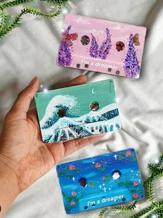 someone is holding two small wallets in their hand, one has an ocean scene on it