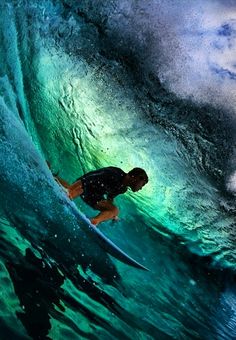 a man riding a wave on top of a surfboard in the ocean at night