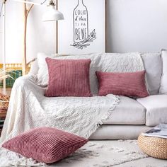 a living room with white furniture and pink pillows on the couch, in front of a wine bottle