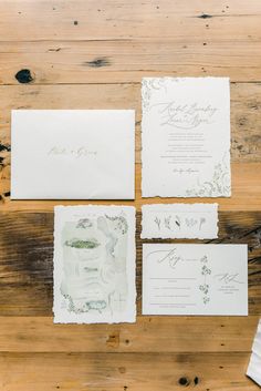 the wedding stationery is laid out on a wooden table