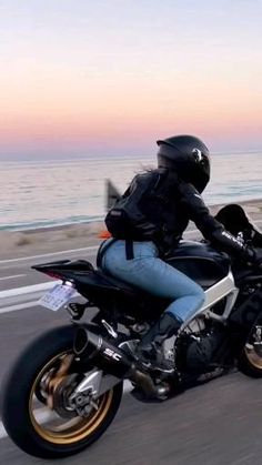 a person riding on the back of a motorcycle down a road next to the ocean