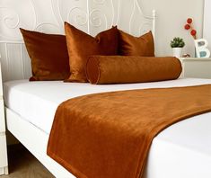 a white bed topped with brown and orange pillows