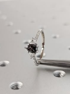 a diamond ring sitting on top of a silver surface with drops of water around it