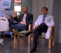 two men sitting in chairs next to each other with medical equipment on the floor behind them